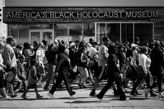 Crowd of people walking past America's Black Holocaust Museum.