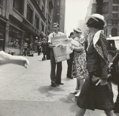 A busy street scene with people walking, a man holding a sign, and various 1940s fashion styles.